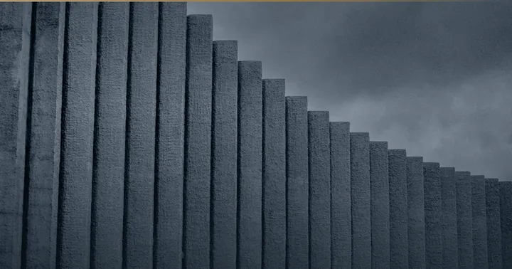 Gestufte Betonwand unter bewölktem Himmel.