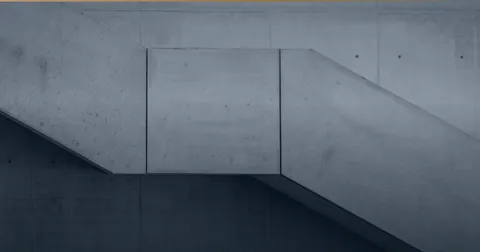 Betontreppe mit zwei Läufen an einer Sichtbetonwand.