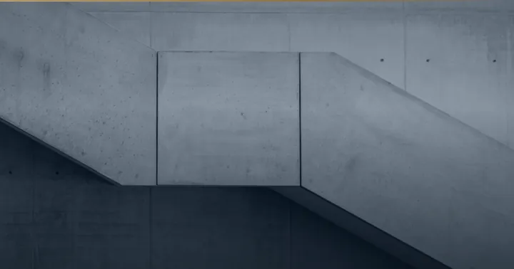 Betontreppe mit zwei Läufen an einer Sichtbetonwand.