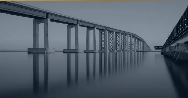 Lange Brücke über ruhigem Wasser.